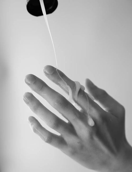 Black and white photo of a hand displaying the texture of creamy fake cum lubricant 150 ml