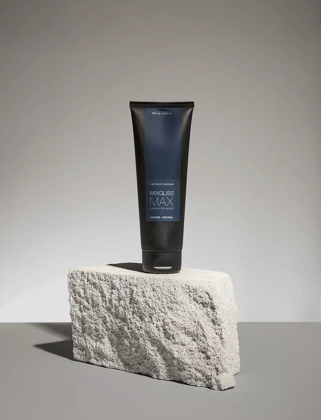 Black and blue tube of Mixgliss Max lubricant on a gray concrete surface