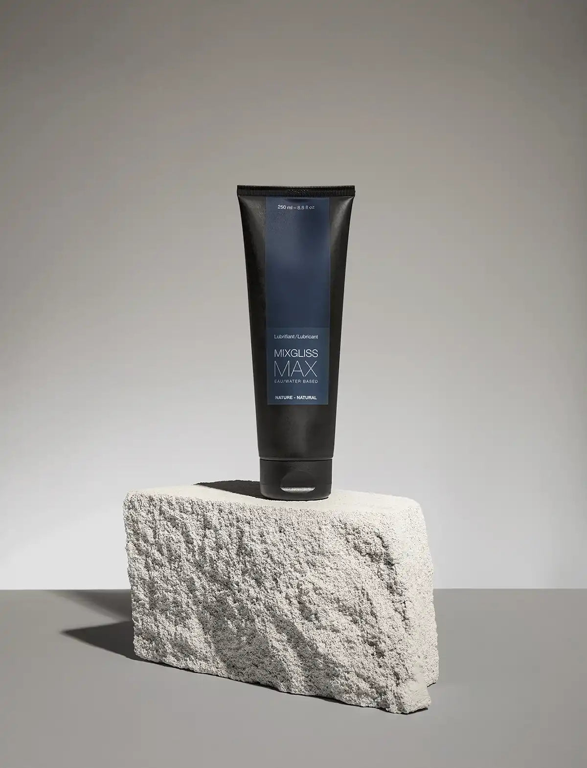 Black and blue tube of Mixgliss Max lubricant on a gray concrete surface