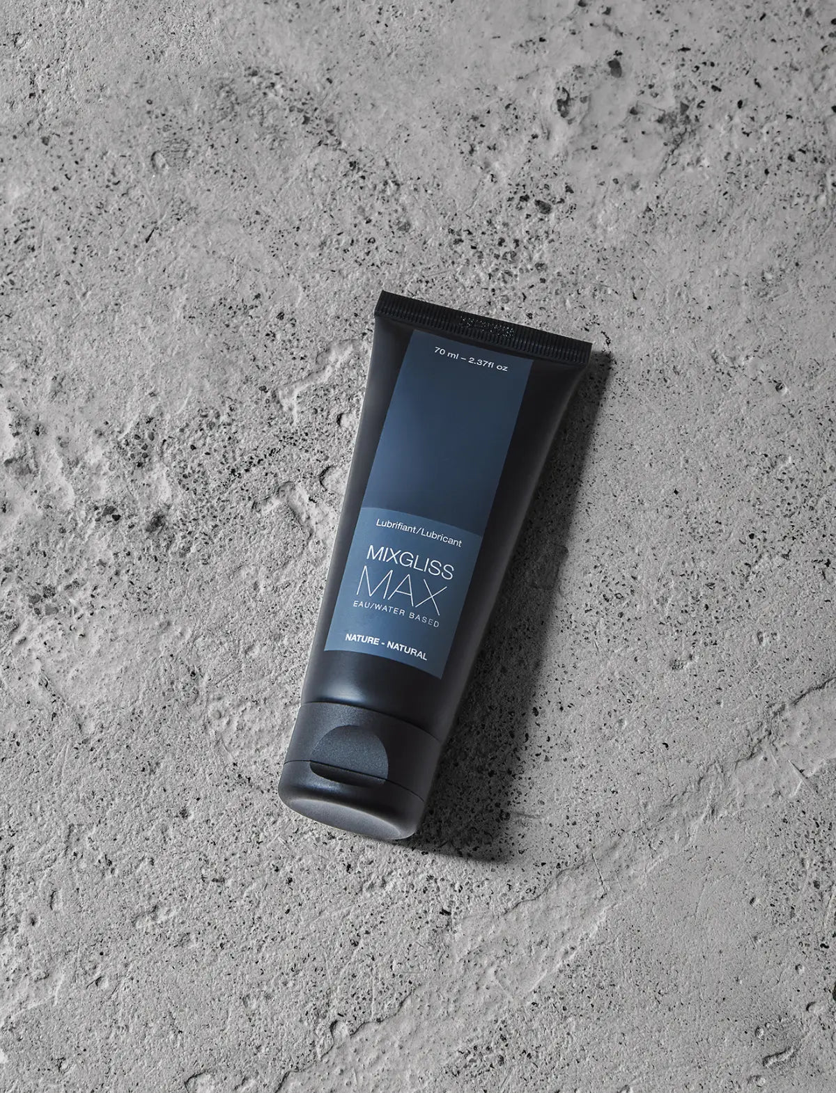 Black and blue tube of Mixgliss Max lubricant on a gray concrete surface